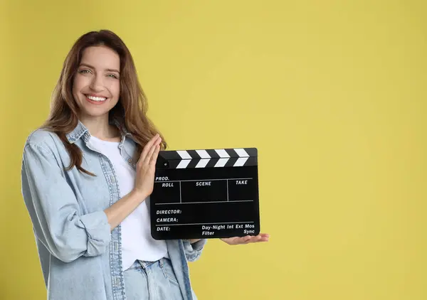 stock image Making movie. Smiling woman with clapperboard on yellow background. Space for text