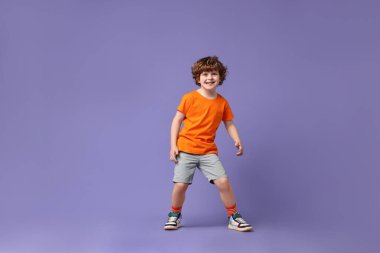 Mutlu küçük çocuk menekşe arka planda dans ediyor