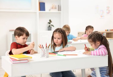 İçerideki masada resim yapan bir grup çocuk.