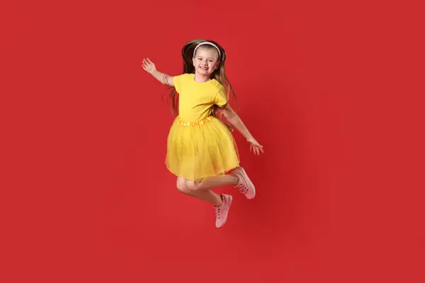 stock image Cute little girl dancing on red background