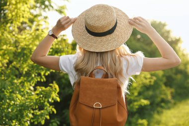 Saman şapkalı genç bir kadın bahar günü açık havada, arka manzara