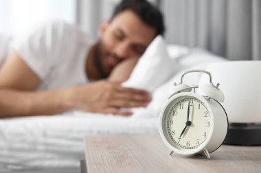 Sabahları yatakta uyuyan adam, çalar saate odaklan.