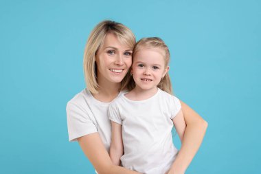 Family portrait of happy mother and daughter on light blue background