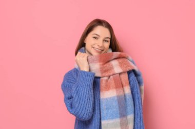 Beautiful woman in warm scarf on pink background