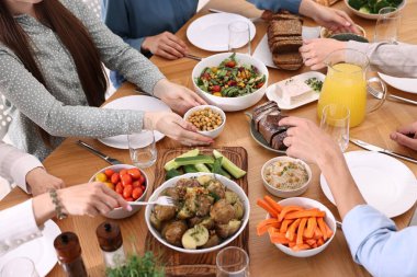 Ahşap masada vejetaryen yemekleri yiyen arkadaşlar, yakın plan.