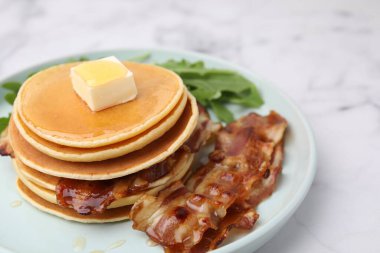 Tereyağlı leziz krepler, kızarmış pastırma ve beyaz mermer masada taze roka, yakın plan.
