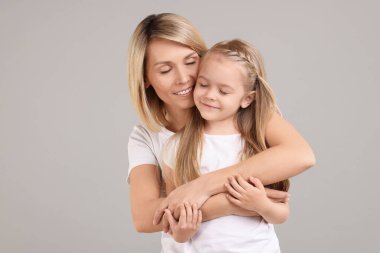 Mutlu anne ve kızı gri arka plan üzerine sarılma