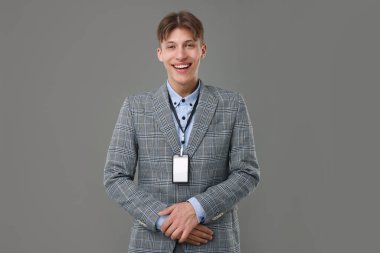 Happy man with blank badge on grey background