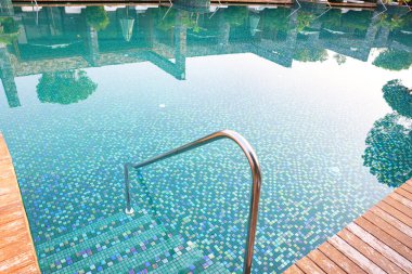 Açık yüzme havuzu, merdivenler ve tırabzanlar tatil köyünde.