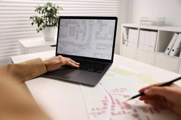 stock image Cartographer working with cadastral map on laptop at white table in office, closeup