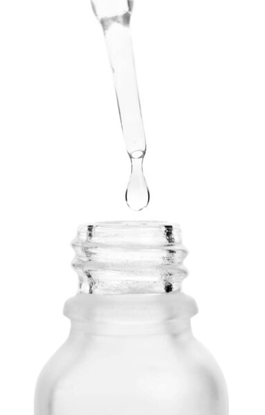 Dripping liquid from pipette into bottle isolated on white, closeup