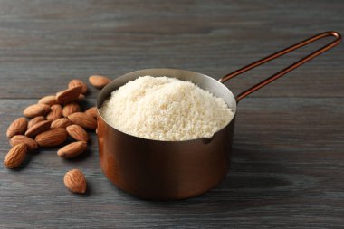 Kepçe içinde taze badem unu ve ahşap masada fındıklar, yakın plan.