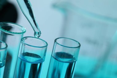 Bulanık arka planda pipetten test tüpüne sıvı damlatılıyor. Yakın plan. Metin için boşluk