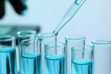 Bulanık arka planda pipetten test tüpüne sıvı damlatılıyor. Yakın plan. Laboratuvar analizi