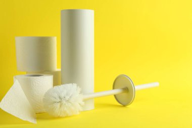Sarı arka planda tuvalet fırçası, tutucu ve rulo kağıt
