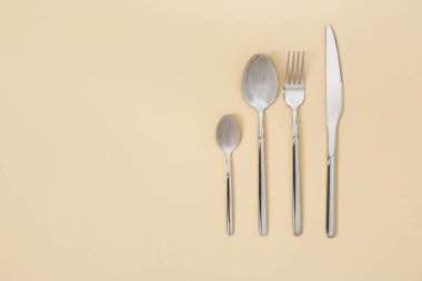 Bej arka planda gümüş çatal bıçak seti. Metin için boşluk