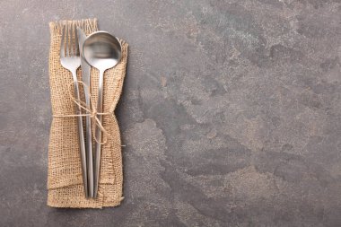 Gri desenli masa üzerinde şık çatal bıçak seti ve peçete, üst manzara. Metin için boşluk