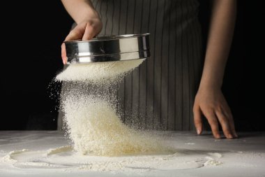 Masada siyah arka planda un süzen kadın, yakın plan.