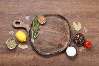 Tahta kesme tahtası, baharatlar, ahşap masada limon ve domates, düz yatak. Metin için boşluk
