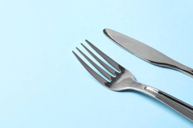 Açık mavi arkaplanda gümüş çatal bıçak takımı, metin için boşluk