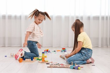 Küçük şirin çocuklar içeride yerde birlikte oynuyorlar.