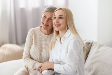 Evde genç bir kadın ve annesinin aile portresi.