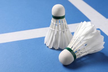 Tüylü badminton mekikleri mavi arka planda, yakın plan. Metin için boşluk