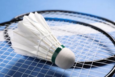 Tüylü badminton topu ve raketleri mavi arka planda, yakın plan