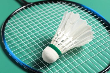 Tüylü badminton topu ve raket yeşil arka planda, yakın plan