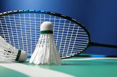 Tüylü badminton mekik penisleri ve raket yeşil masada mavi arka planda, yakın plan