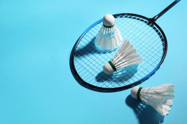 Tüy badminton mekik horozları ve açık mavi zemin üzerinde raket, metin için boşluk