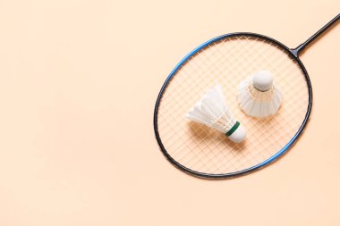 Badminton mekik penisleri ve raketi bej arka planda, üst manzara. Metin için boşluk