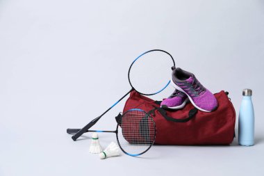 Badminton seti, çanta, spor ayakkabıları ve gri arka planda şişe, mesaj için boşluk