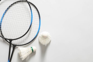 Tüylü badminton mekikleri ve raketleri gri arka planda, düz yatıyordu. Metin için boşluk
