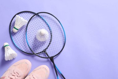 Menekşe arka planda badminton topları, raketler ve spor ayakkabıları, düz yatış. Metin için boşluk