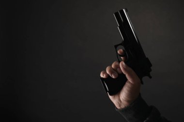 Silahlı soygun. Siyah arka planda silahı olan tehlikeli bir suçlu, yakın plan. Metin için boşluk