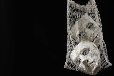 Siyah arka planda plastik maskeli ağ torbası, mesaj için yer. Tiyatro performansı
