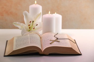 Çarmıhta zincir, yanan mumlar, çiçekler ve inciller beyaz masada, yakın plan. Hıristiyanlık Dini