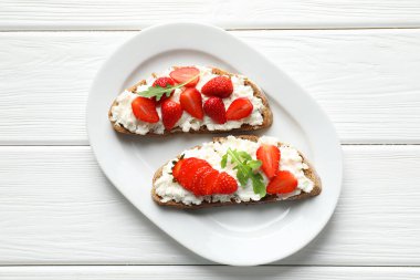 Lezzetli ricotta bruschetta çilekli ve roka beyaz ahşap masa, üst manzara