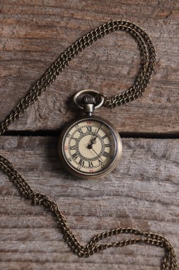 Zincirli cep saati, ahşap masa, üst manzara.