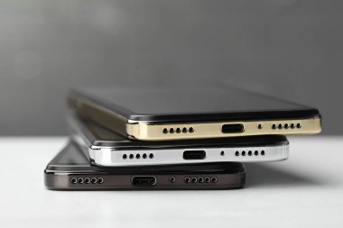 Stack of modern smartphones on white table, closeup
