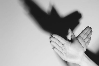 Kadın hafif arka plandaki kuş gibi el hareketi yapıyor, mesaj için yere yakın çekim yapıyor. Siyah ve beyaz etkisi