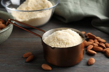 Kepçe içinde taze badem unu ve ahşap masada fındıklar, yakın plan.