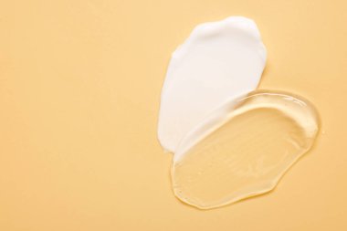 Soluk sarı arka planda yüz kremi örnekleri, üst manzara. Metin için boşluk