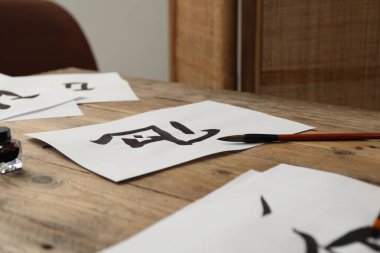 Kaligrafi. Kağıt üzerinde yazılı hiyeroglifler ve ahşap masa fırçası.