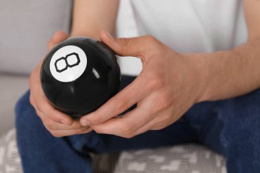 Sihirli sekiz topu tutan adam kapalı alanda, yakın plan.