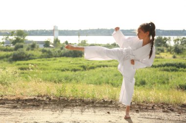 Kimonolu şirin kız dışarıda karate yapıyor.