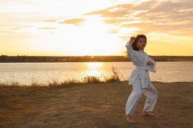 Gün batımında nehirde karate yapan kimonolu tatlı bir kız.