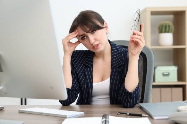 Overwhelmed office worker sitting at table with computer indoors