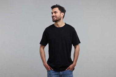 Gri arka planda siyah tişörtlü gülen adam.